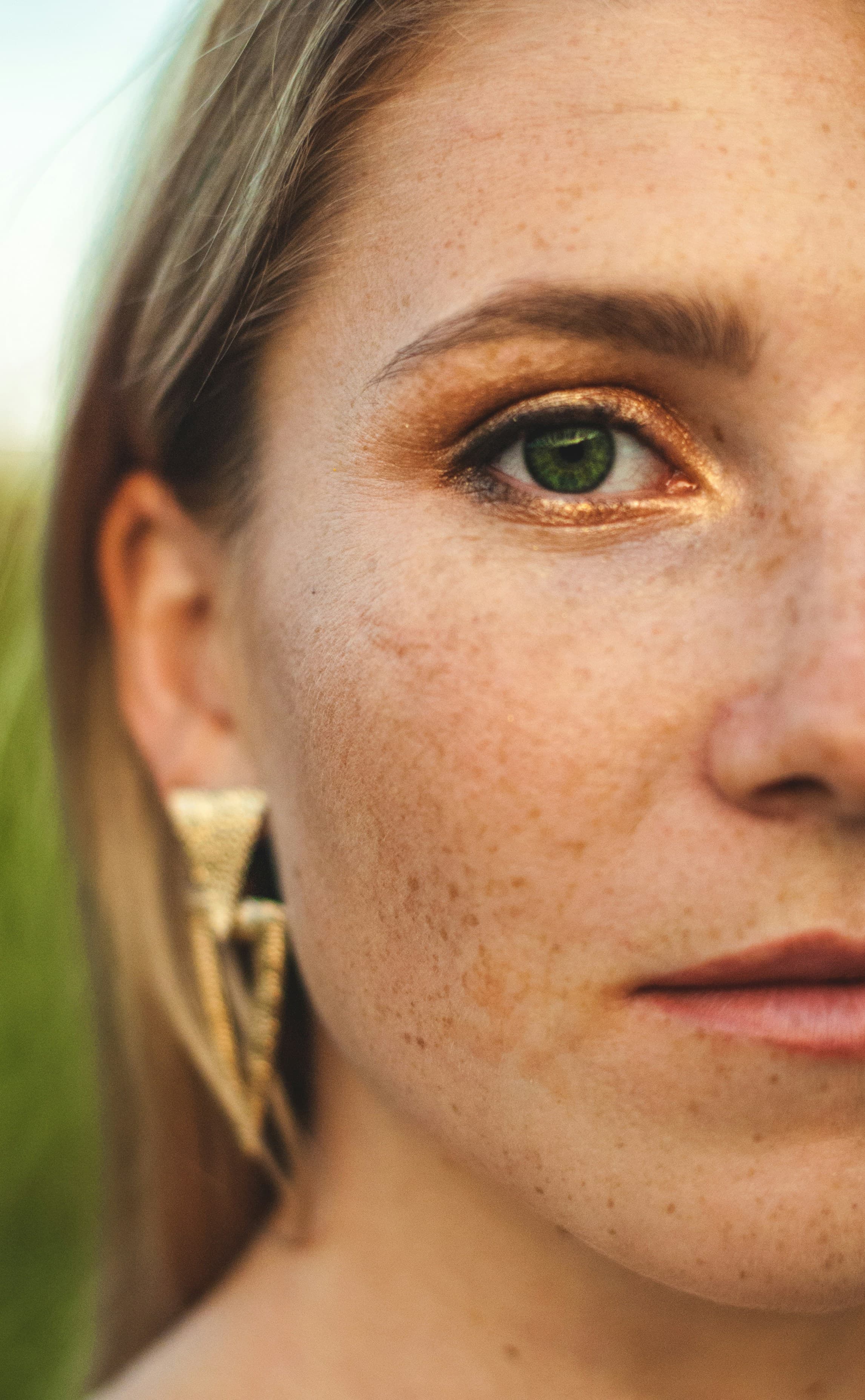 Close-up half portrait of a woman with freckled skin and green eyes