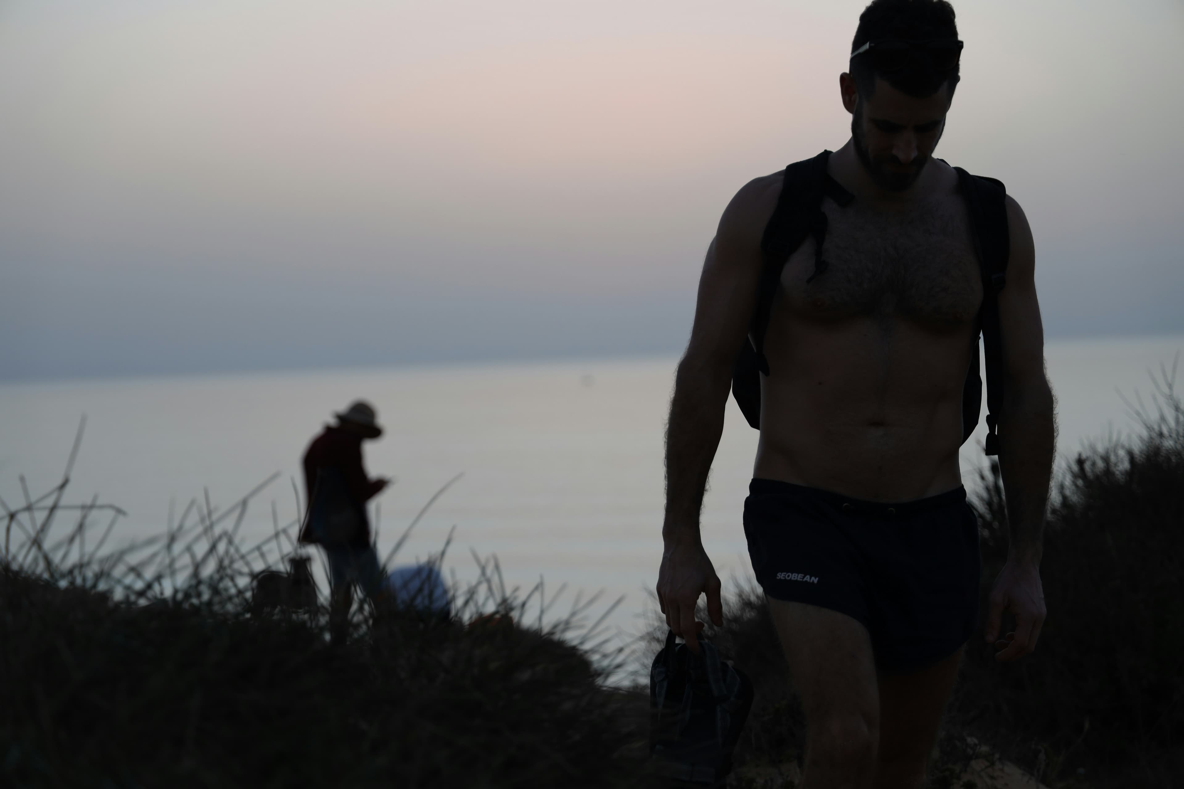 Athlete carrying a weight at dusk on a coastal hillside