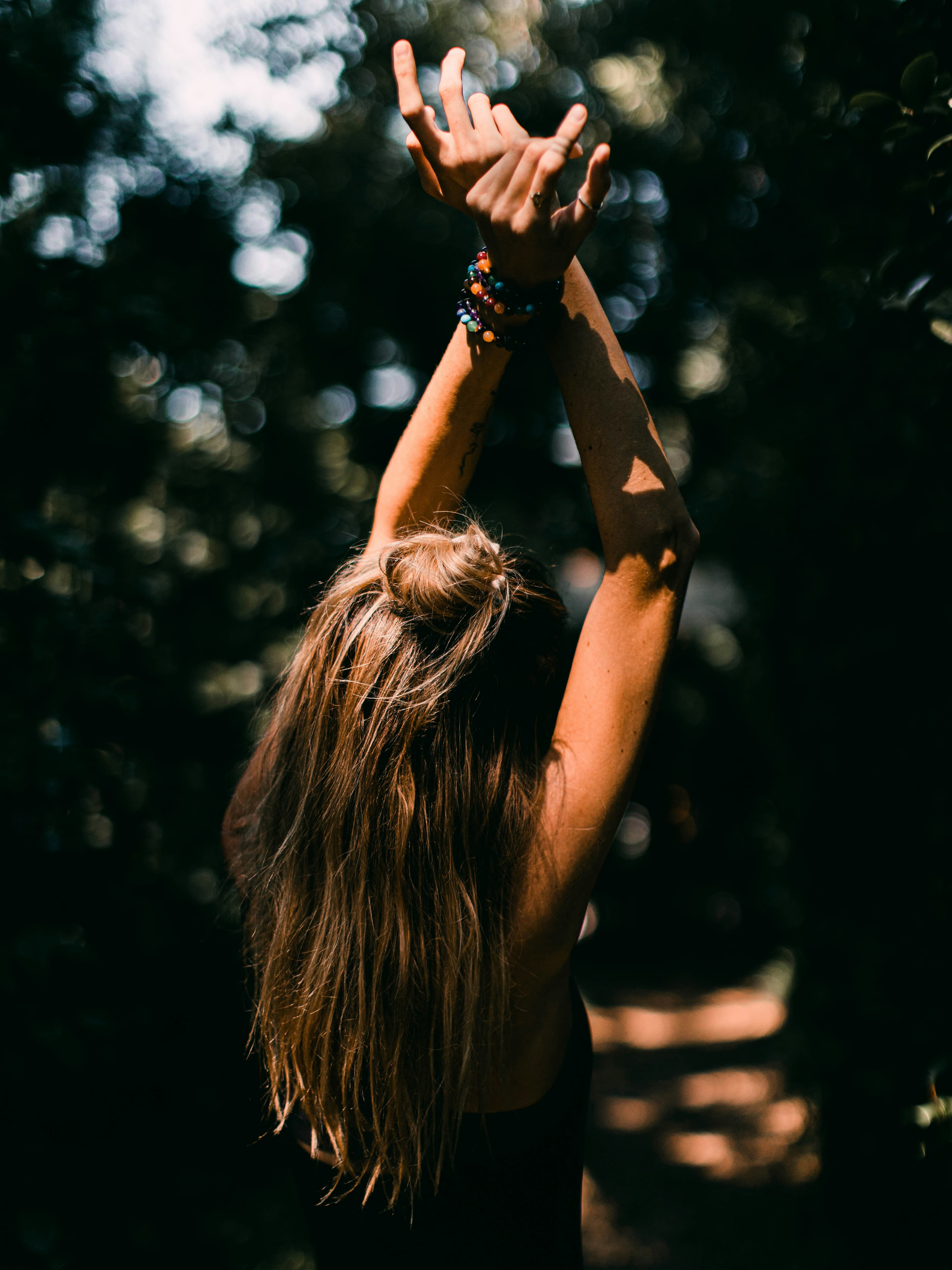 Woman with arms raised in dappled forest light