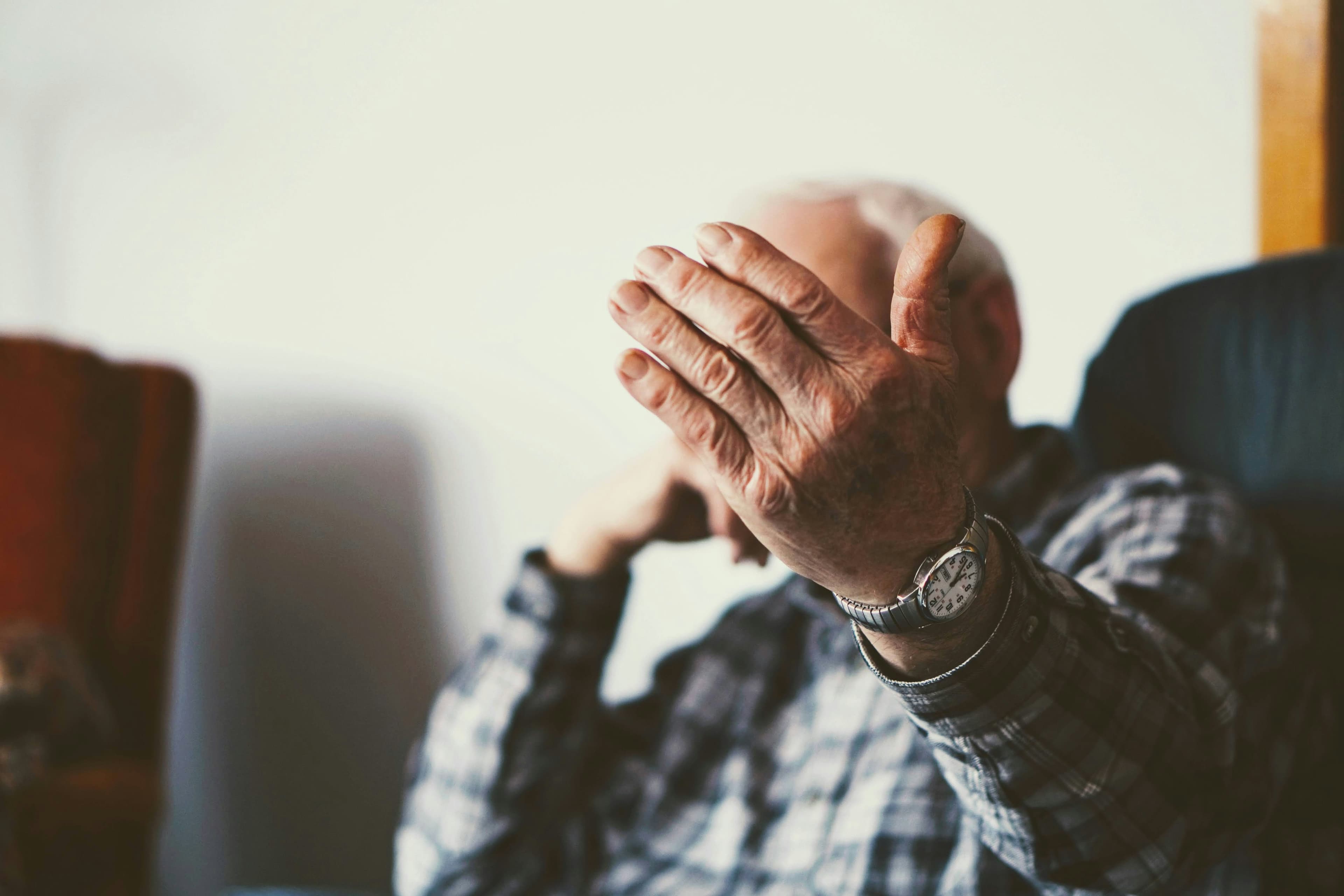 Older man with hand over face, sitting quietly