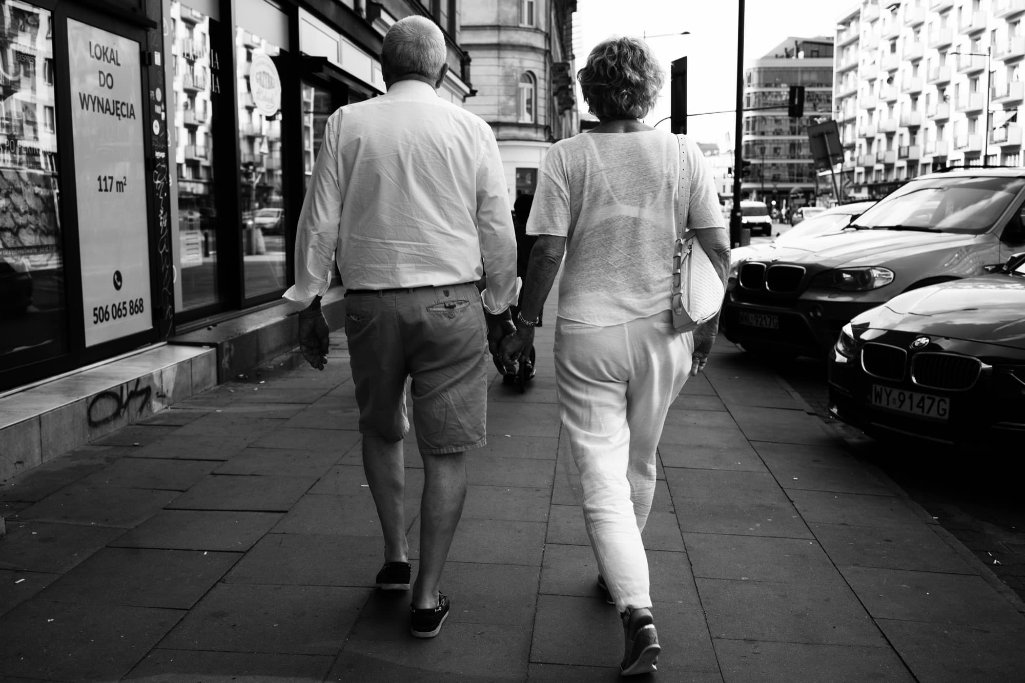 Older couple walking hand in hand on a city street, black and white