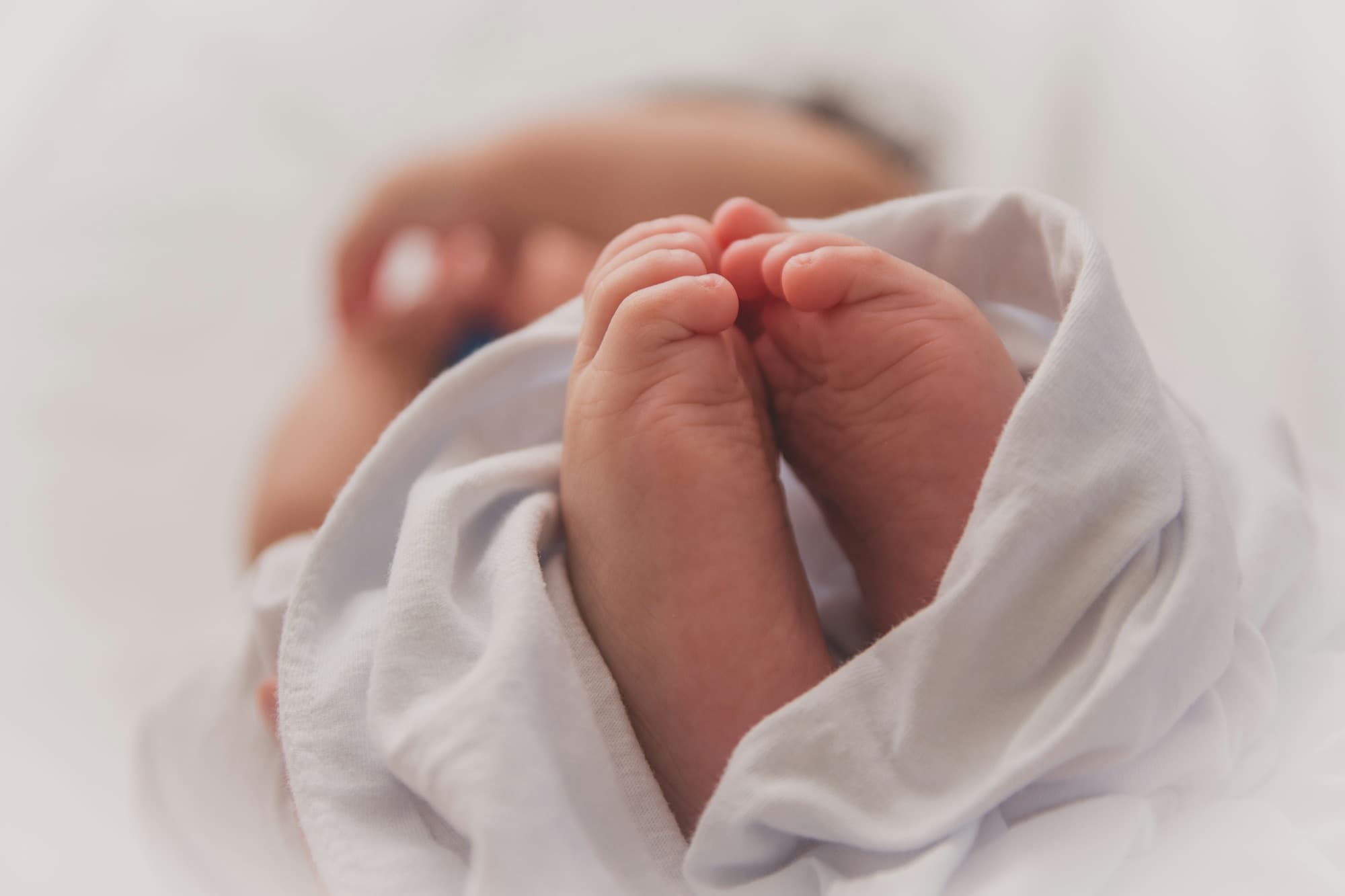 Newborn baby feet wrapped in a white cloth