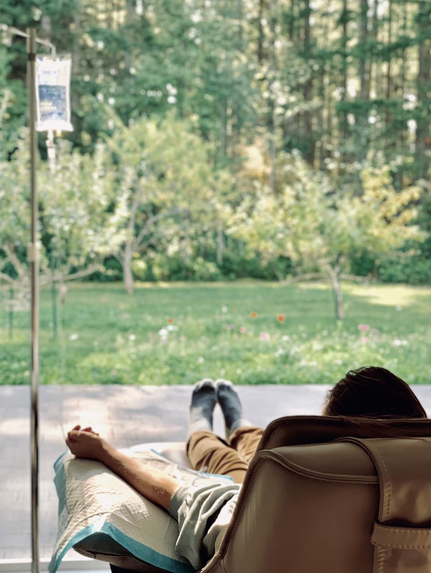 Patient relaxing in a chair during an IV therapy session with a view of the garden at Dr. Kefferputz's Salt Spring Island office