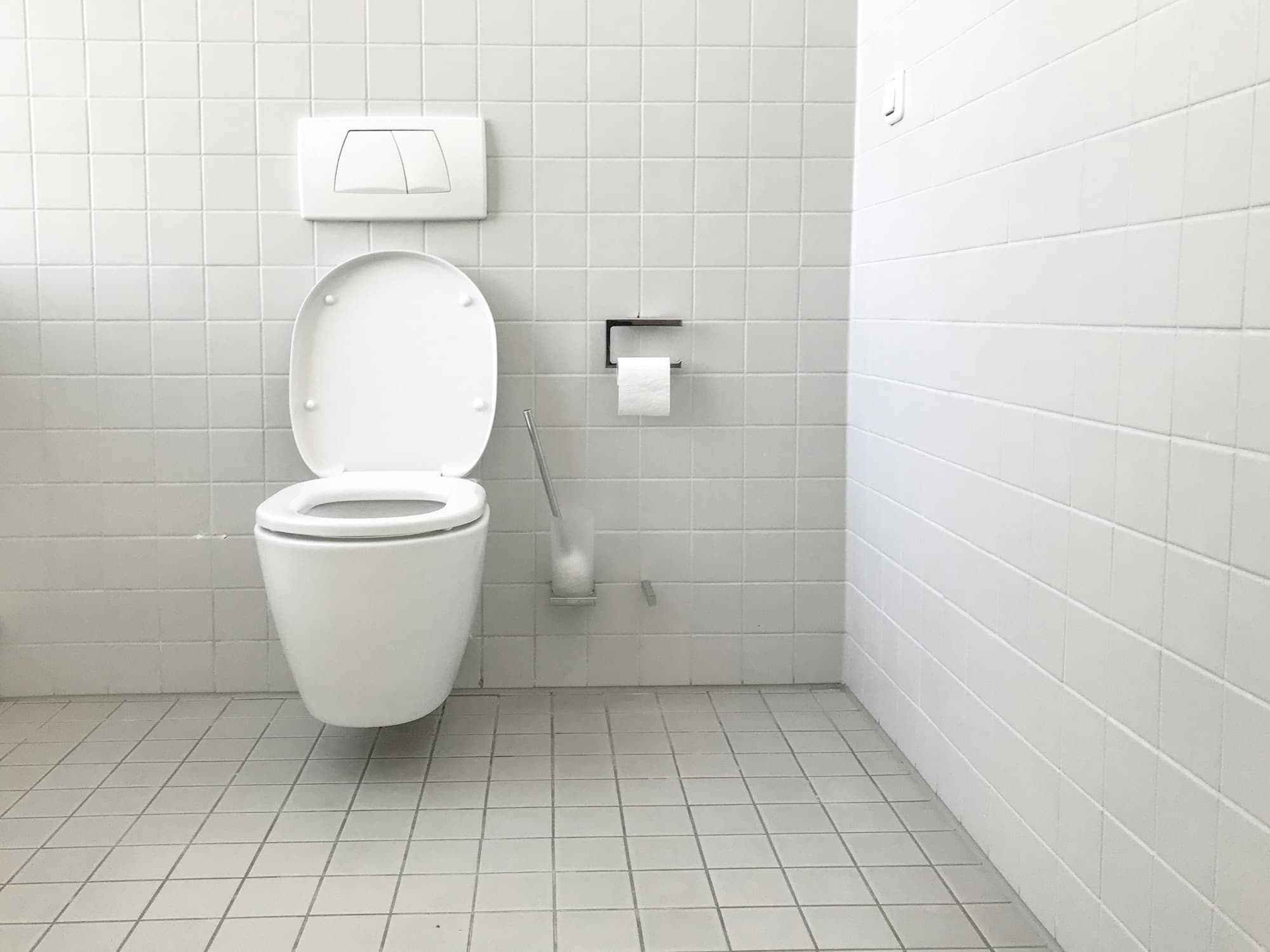 Clean white tiled bathroom with wall-hung toilet