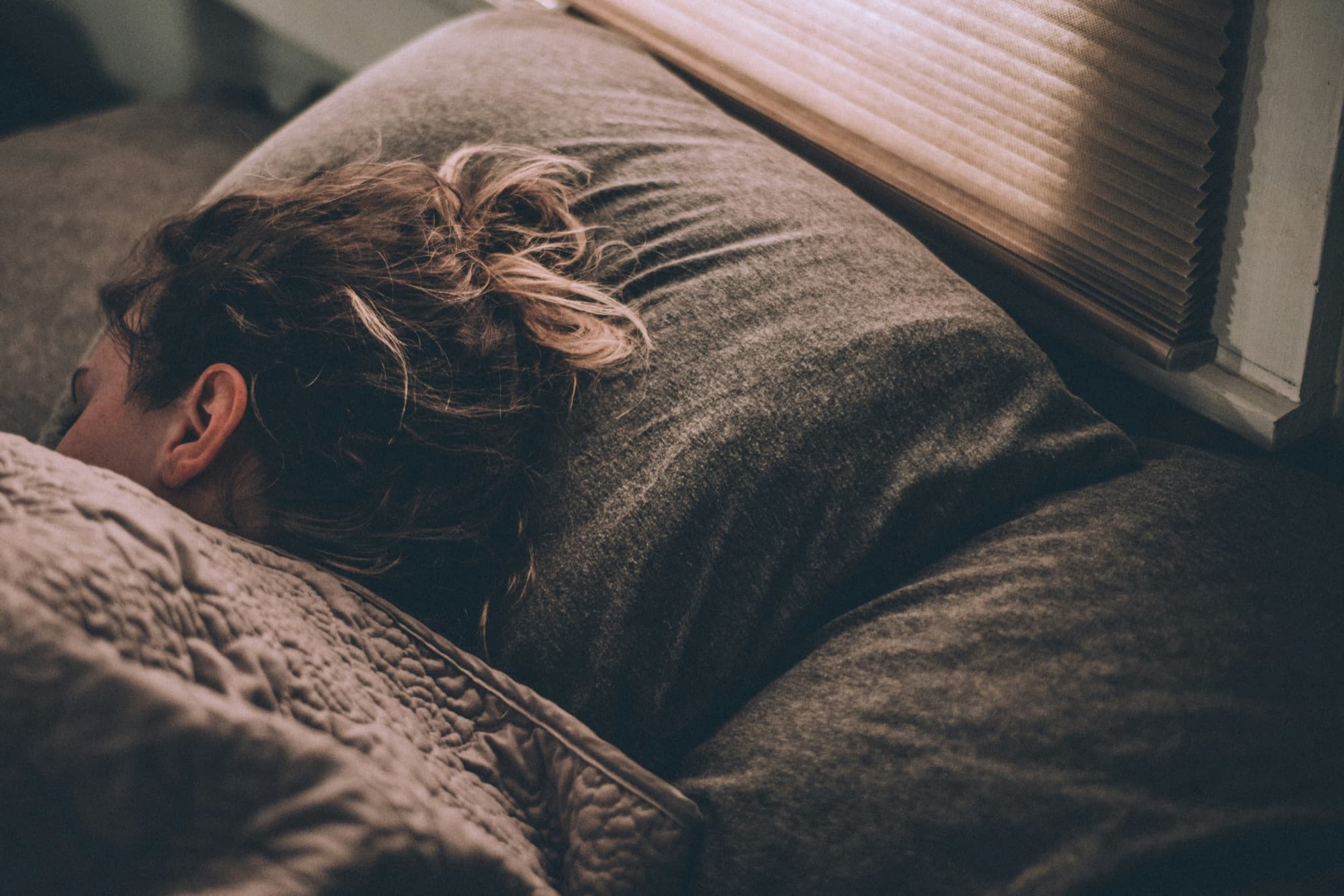 Person sleeping under grey blanket