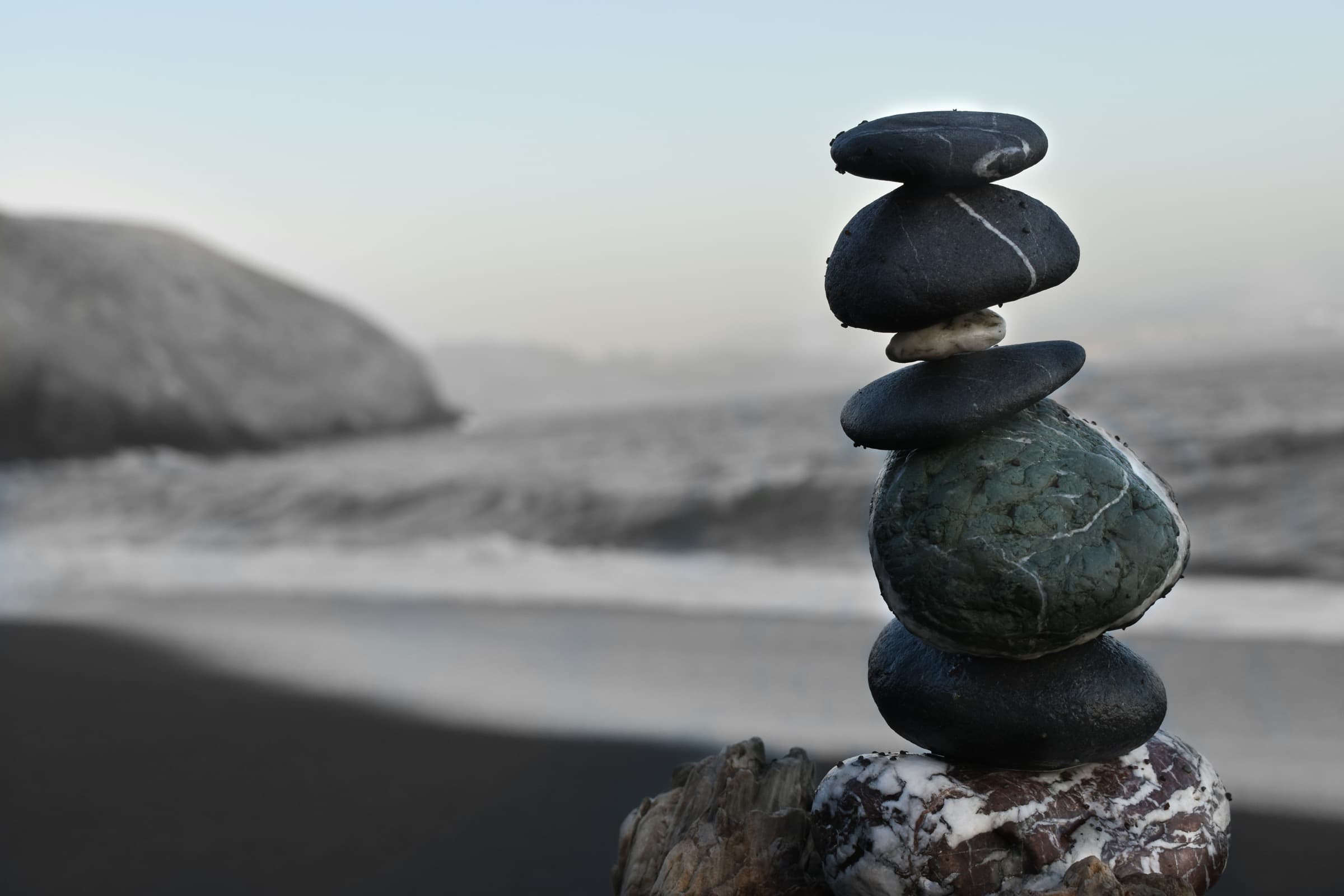 Stack of dark stones balanced on a rocky beach