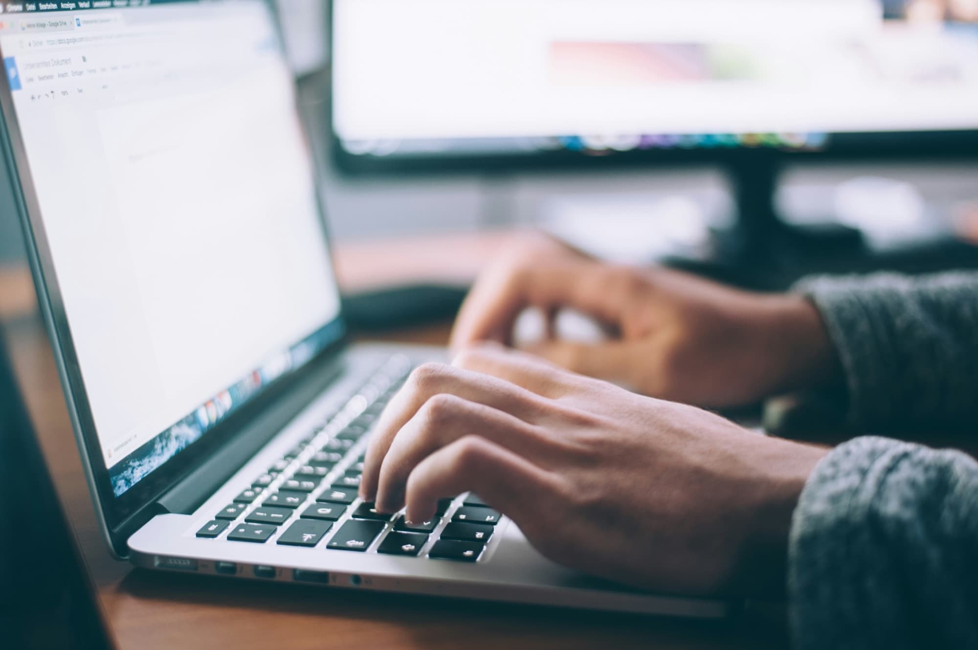 Hands typing on a laptop for a telemedicine consultation